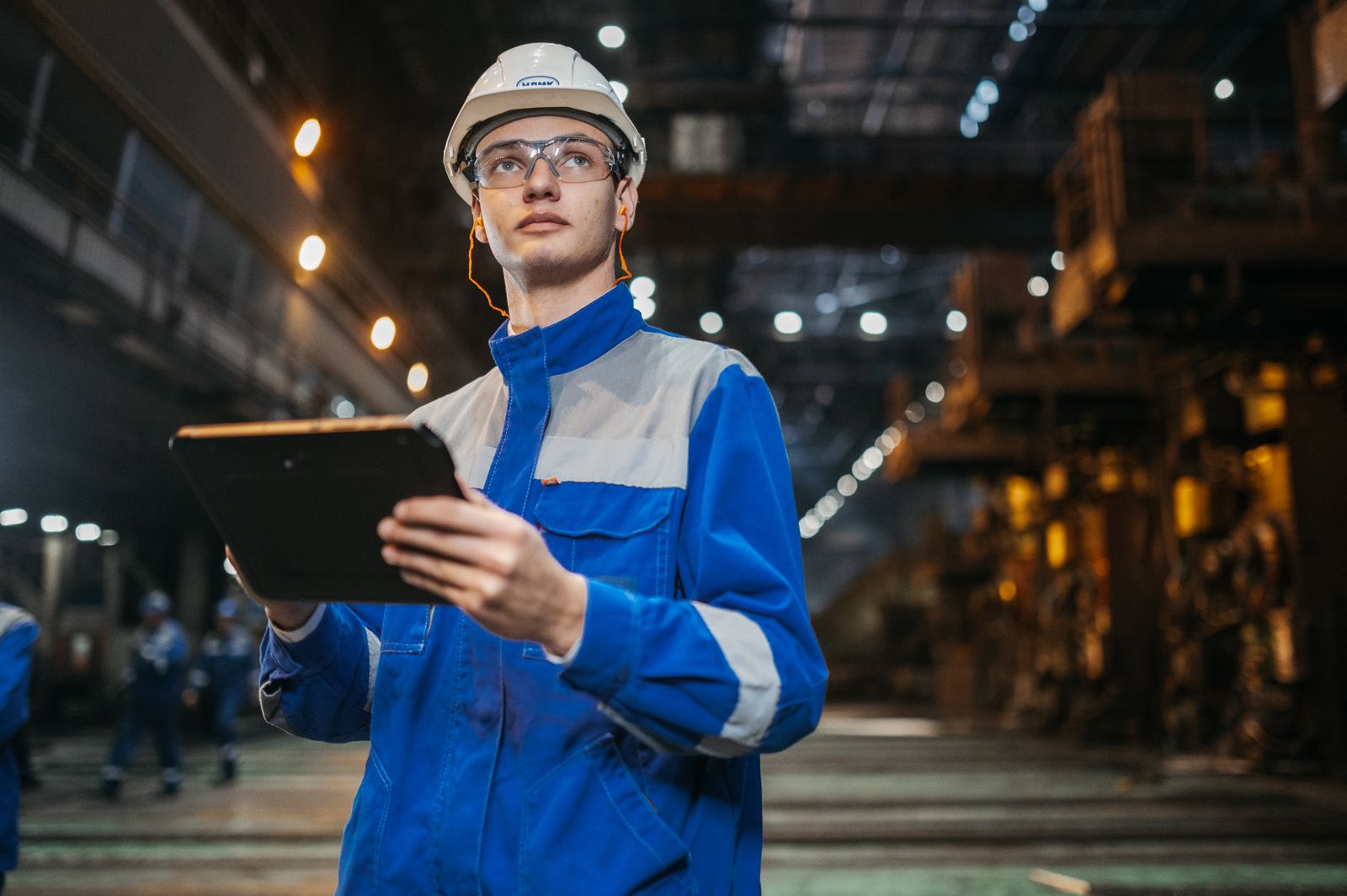 Engineer using a tablet in a factory, showing the benefits of digital twin technology for students entering industry
