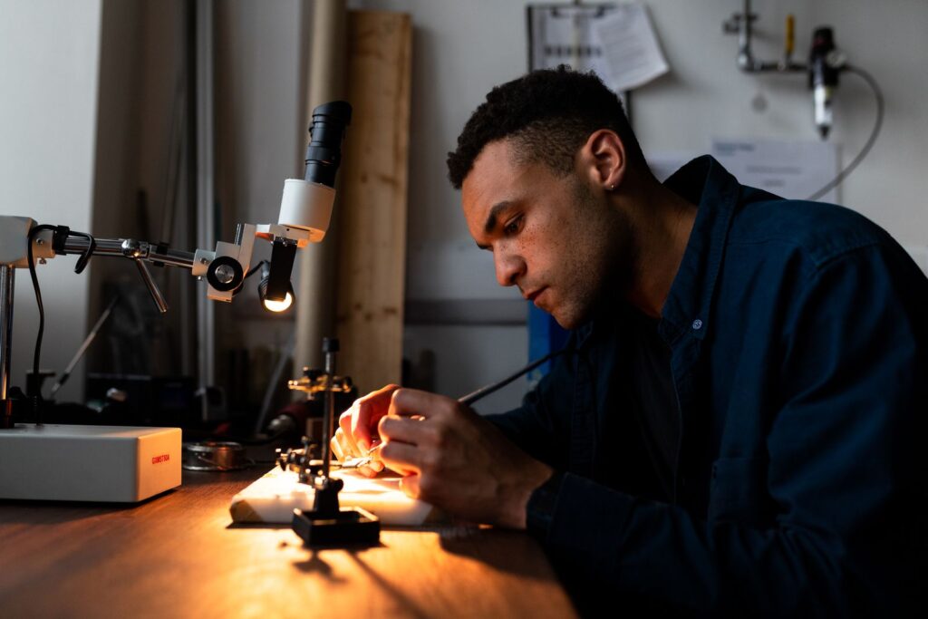 A student soldering a circuit in a workshop, a skill supported by a digital twin for engineering education