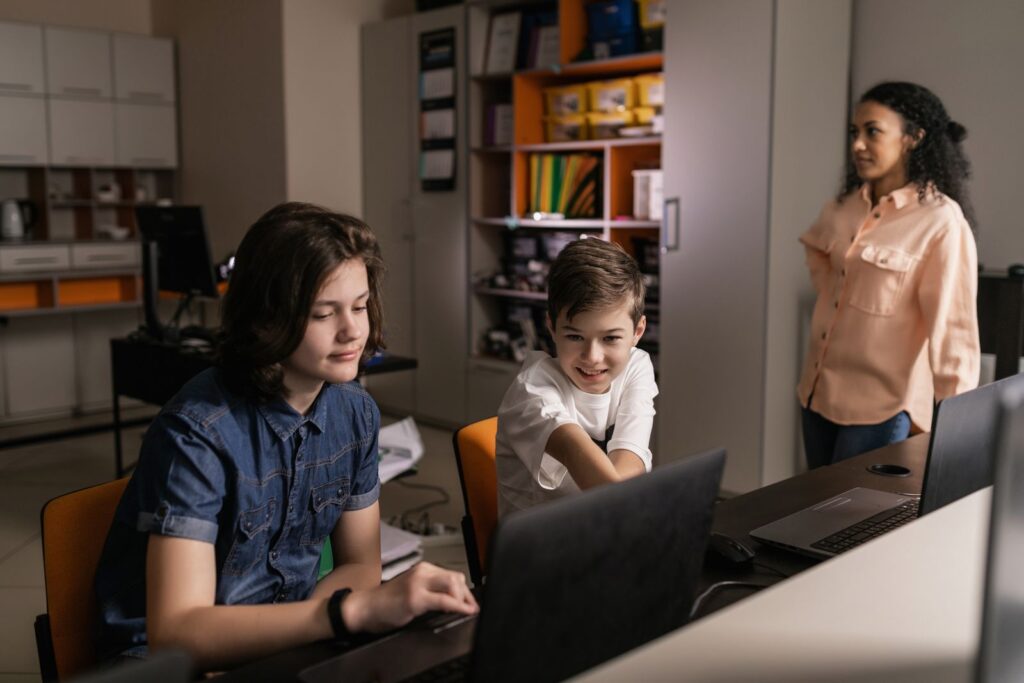 Students using laptops in a classroom to run a digital twin in education project