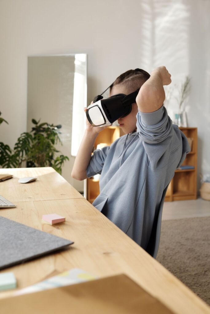 Boy at a desk wearing a VR headset, using extended reality for immersive learning at school