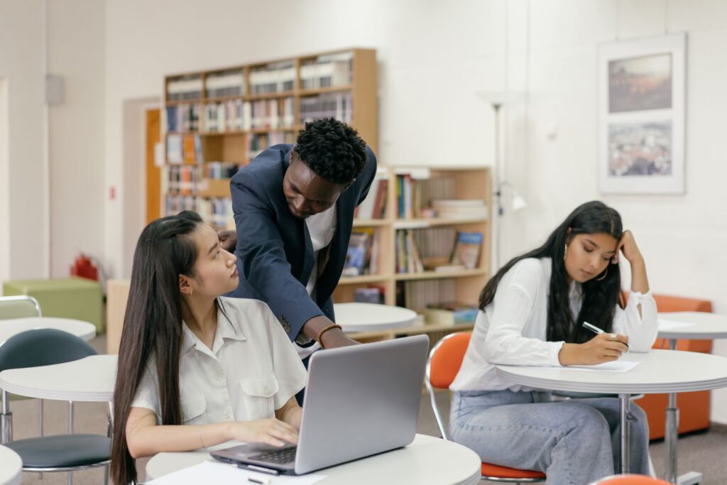 Teacher guiding a student on a laptop, showing the teacher role in extended reality in education