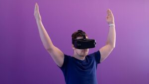 A student with arms raised inside a VR headset, exploring the metaverse in education